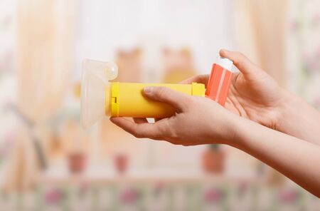 Portable nebulizer with child mask in female hand, on light backgroundの写真素材