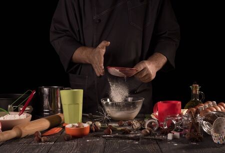 Set of products and devices for baking, Baker's hands sifted flour, isolated on black backgroundの写真素材