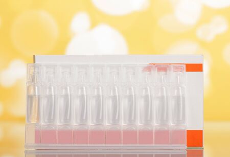 Carton box and ampoules of drug solution on light yellow backgroundの写真素材