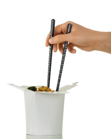 Woman's hand with sticks dials noodles from the wok box, isolated on white backgroundの写真素材