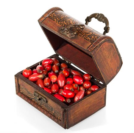 Wooden box, full of fruits of medicinal plants of rose isolated on white backgroundの写真素材