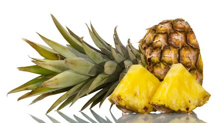 Cut off top of pineapple with leaves, next to slices isolated on white backgroundの写真素材