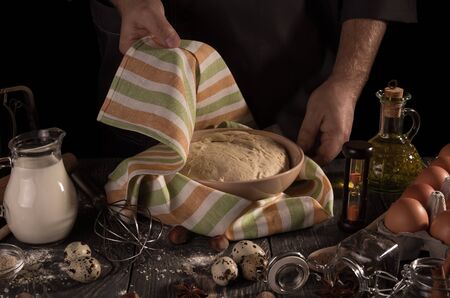 Yeast dough for proofing in the bowl under the towel, isolated on black backgroundの写真素材