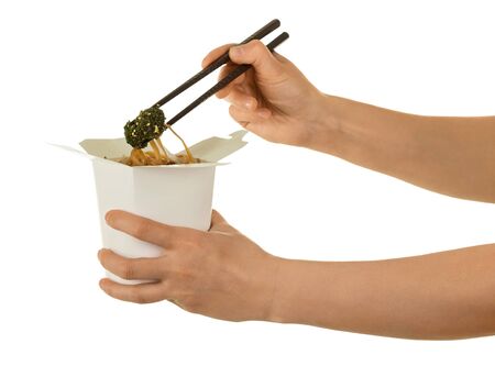 Female hand takes of sticks, spicy Chinese noodles from wok box, isolated on white backgroundの写真素材