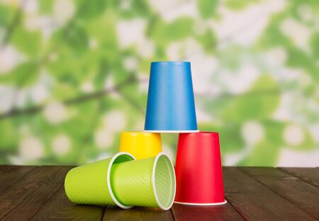 Set of multicolored plastic cups on brown wooden tableの写真素材