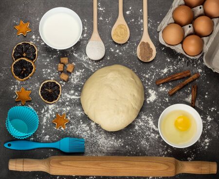 Ready-made dough lump, eggs and sour cream, baking molds, on gray work surfaceの写真素材
