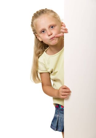 Little girl with long blond hair Peeps out from behind poster isolated on white backgroundの写真素材
