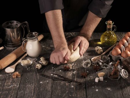 On table food and cooking utensils, dough in hands of Baker, isolated on black backgroundの写真素材