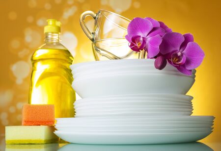 Plates and cups, dish detergent, sponges, Orchid flower on yellow backgroundの写真素材