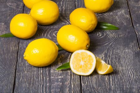 Bright yellow lemons and pieces scattered on dark wooden surface. Closeupの写真素材