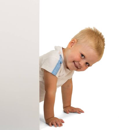 Little smiling boy peeking out from behind an empty Billboard isolated on white backgroundの写真素材