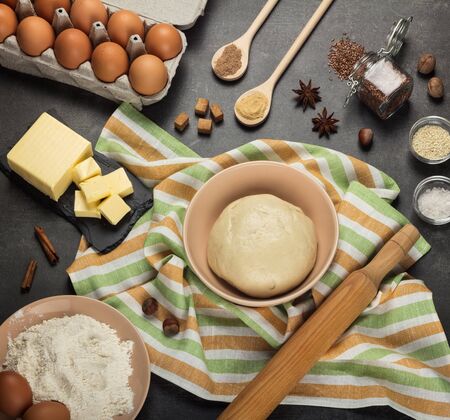 Set of products and spices, finished dough in bowl on towel on gray work surfaceの写真素材