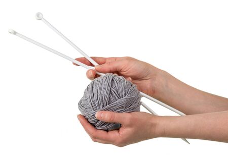 Ball of soft gray yarn and knitting needles in woman hands isolated on white backgroundの写真素材