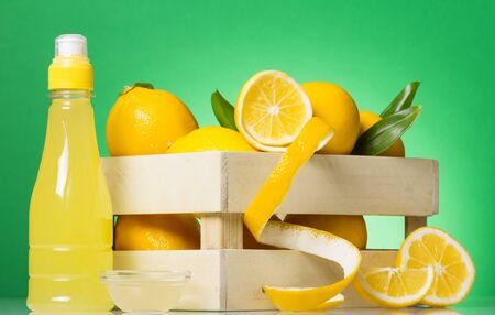 Lemon juice, fruit in box, lemon slice with peel on green backgroundの写真素材