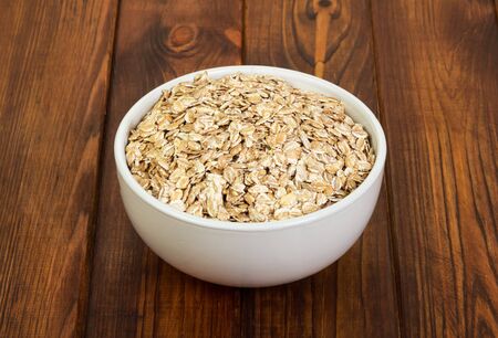 A bowl of oatmeal close-up on a background of dark wood.の写真素材