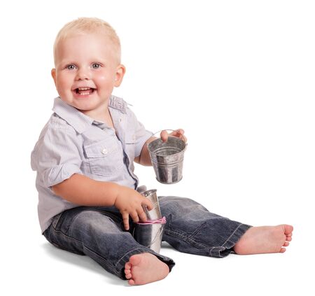 Cute little boy in a bright with stripes shirt and jeans sitting holding a small bucket isolated on white background.の写真素材