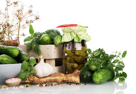 Wooden box and a bowl of green cucumbers, jar of pickles, spice isolated on white background.の写真素材