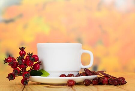 Berry rosehip and cup of tea on a background of autumn leaves.の写真素材