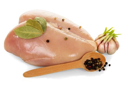 Raw chicken breast, garlic, bay leaves and black pepper in a spoon isolated on white background.の写真素材