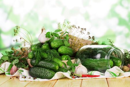 A pile of fresh cucumbers in a glass jar, spices on an abstract green background.の写真素材