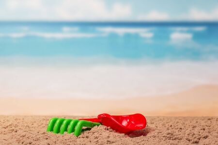 Children's toys shovel and rake in the sand on the sea background.の写真素材