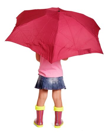 Little girl in a blouse, a skirt and rubber boots with an umbrella standing isolated on white background. Back view.の写真素材