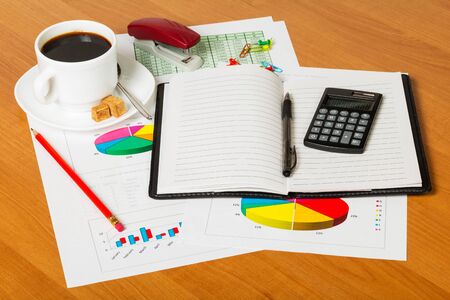 Notebook, calculator, cup of coffee and office supplies on the desktop background.の写真素材