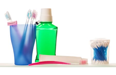 Glass with toothbrush and disposable razor, toothpaste, elixir and cotton swabs isolated on white background.の写真素材