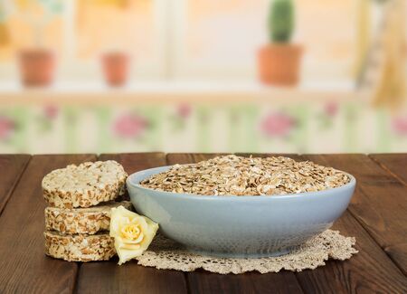 A bowl of oatmeal, crackers and rose against the background of the kitchen.の写真素材