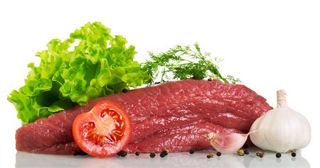 A piece of raw beef, tomato, lettuce, dill and spices isolated on white background.の写真素材