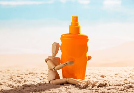 Wooden mannequin with sunscreen on the seashore.の写真素材