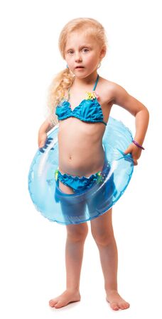 Charming little blond girl in a swimsuit holding an inflatable ring isolated on white background.の写真素材