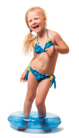 Little blond girl in a bathing suit and inflatable ring on legs isolated on white background.の写真素材