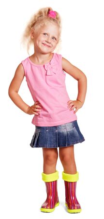 A cute little blond girl in a pink blouse and blue skirt, colorful rubber boots isolated on white background.の写真素材