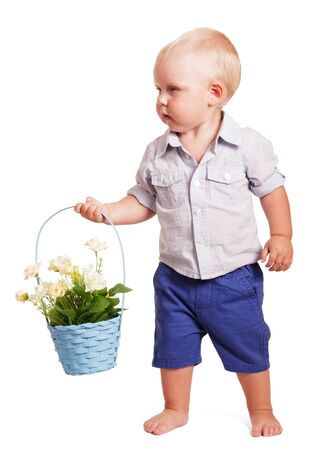 Little boy in bright striped shirt and blue shorts standing and holding a basket with roses isolated on white background.の写真素材