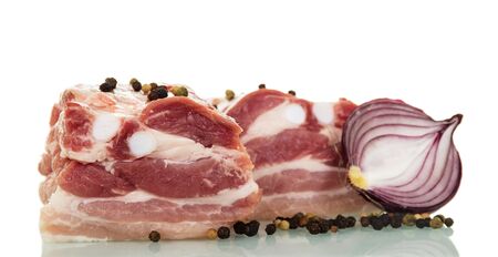 Pieces of raw pork brisket, half of the onion and pepper isolated on white background.の写真素材