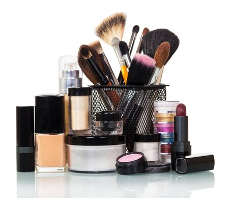 Cosmetic brush, eye shadow, liquid base, lipstick and a jar of cream isolated on white background.の写真素材