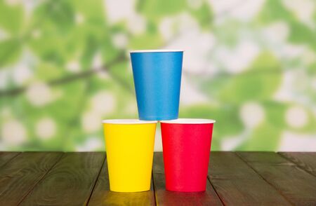 Bright disposable paper cups on abstract green background.の写真素材