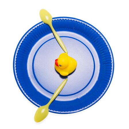 Disposable paper plates, plastic spoons and a rubber duck isolated on white background.の写真素材