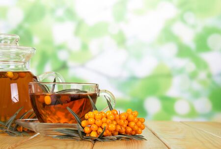 Pitcher and a glass of beverage, bunch of sea buckthorn on abstract green background.の写真素材