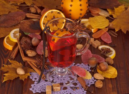 Mulled wine spices and fruit, nuts, candy on the background of autumn leaves.の写真素材