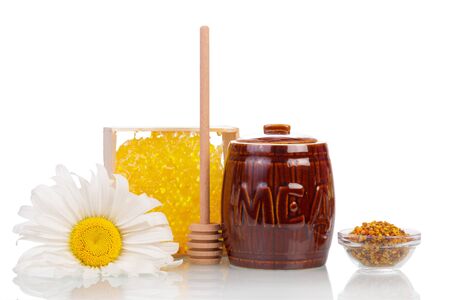 A barrel of honey, honeycomb, pollen bowl, wooden ladle and camomile isolated on white background.の写真素材