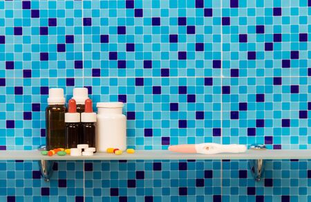 Shelf in a bathroom with a pregnancy test, medicines and pills on the abstract blue background.の写真素材