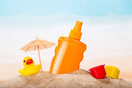 Sunscreen, umbrella and tos in the sand against the sea.の写真素材