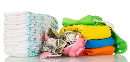 Stacks of disposable, cloth diapers and broken piggy bank with dollars isolated on white background.の写真素材