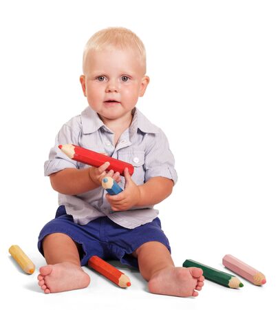 Cute little boy is sitting and holding a large pencils isolated on white background.の写真素材