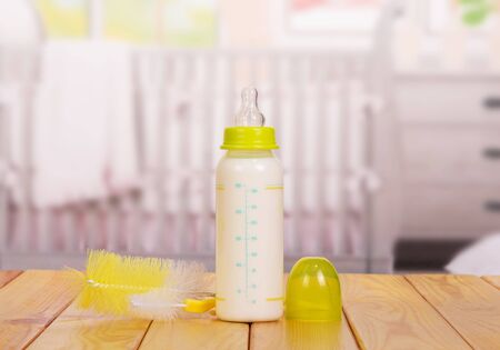 Baby bottle with milk and brush for washing bottles in the background of the kitchen.の写真素材
