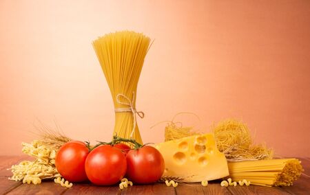 Pasta, cheese and tomatoes on a brown background.の写真素材