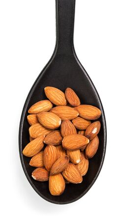 Peeled almonds in a black spoon isolated on white background.の写真素材