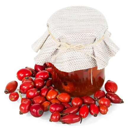 Rosehip berries and a glass jar with a drink isolated on white background.の写真素材